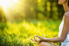Intuitive eating and meditation - woman meditating in a sunny green field