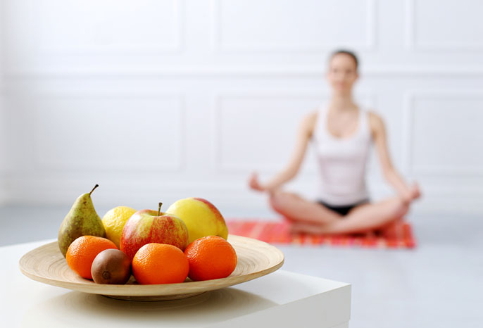 Intuitive eating - bowl of fresh fruit with a woman meditating